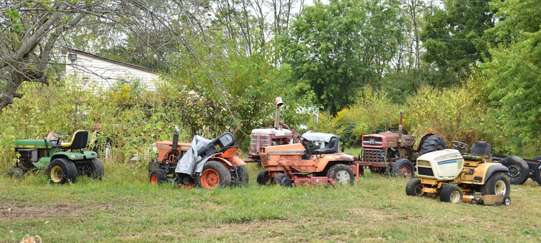 Several lawnmowers parked in a grassy field.